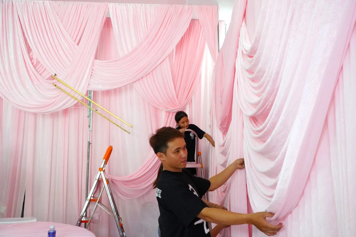 Nhân viên thi công đang lắp đặt phông nền vải voan màu hồng pastel cho tiệc cưới. (Ảnh: Sưu tầm)
