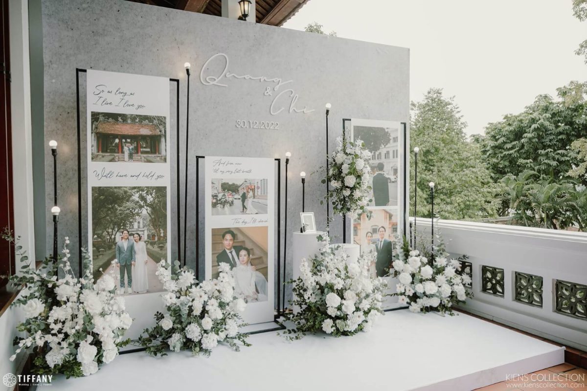 Photobooth chụp ảnh cưới tone trắng – xám hiện đại, trang trí hoa tươi tông trắng và ảnh kỷ niệm của cặp đôi. (Ảnh: TIFF.vn) 