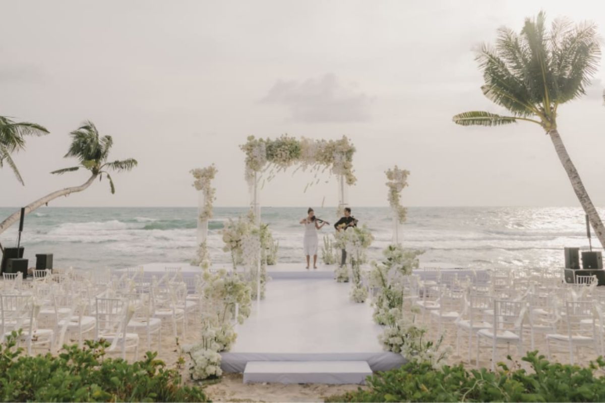 Không gian lễ cưới ngoài trời bên bờ biển Phú Quốc, setup sang trọng với bàn tiệc và backdrop hoa tươi. (Ảnh: Sưu tầm)