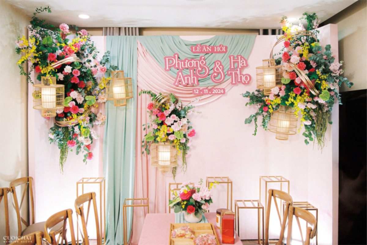Backdrop màu hồng pastel kết hợp xanh mint, hoa tươi rực rỡ và đèn tre, mang đến vẻ đẹp ngọt ngào, trang nhã và đậm chất lễ ăn hỏi Việt Nam hiện đại. (Ảnh: TIFF.vn)