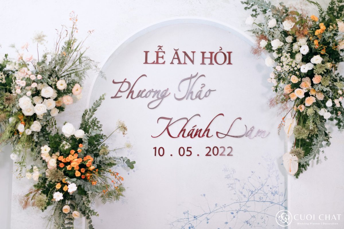 Backdrop đám hỏi trang trí theo concept Greenery Wedding, kết hợp lá xanh, hoa tươi và sắc cam ấm áp, mang vẻ đẹp hiện đại pha chút truyền thống. (Ảnh: TIFF.vn)