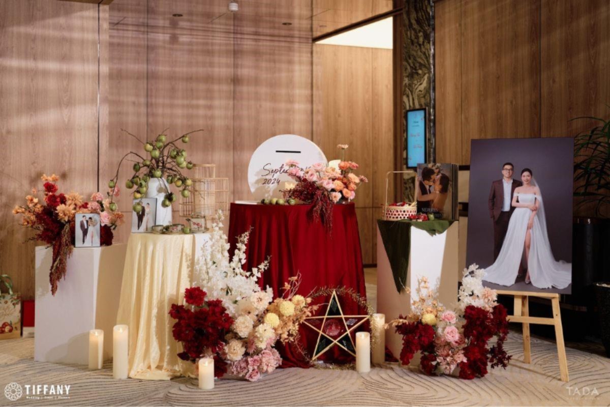 Bàn gallery tiệc cưới tại Pan Pacific Hanoi với tông đỏ đô – nude sang trọng, điểm nến tealight và hoa hồng pastel tạo không gian lãng mạn, tinh tế. (Ảnh: TIFF.vn)