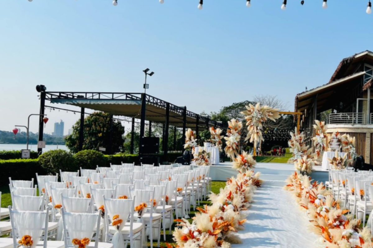 Tiệc cưới ngoài trời phong cách Bohemian sang trọng với lối đi trải thảm trắng và trang trí hoa khô màu trắng - cam. (Ảnh: Nắng Sông Hồng) 