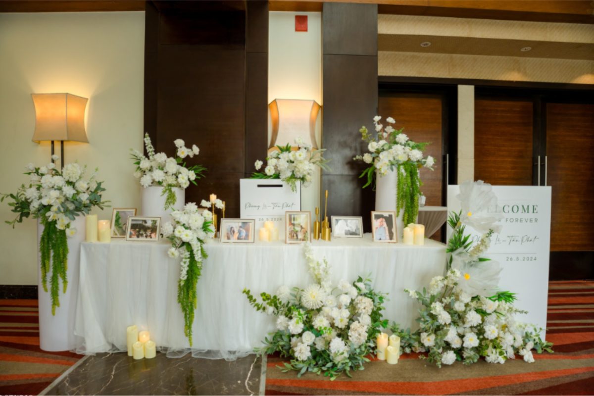 Bàn đón tiếp khách mời với sổ ký tên, hoa tươi và chi tiết trang trí tinh tế. (Ảnh: Sưu tầm)