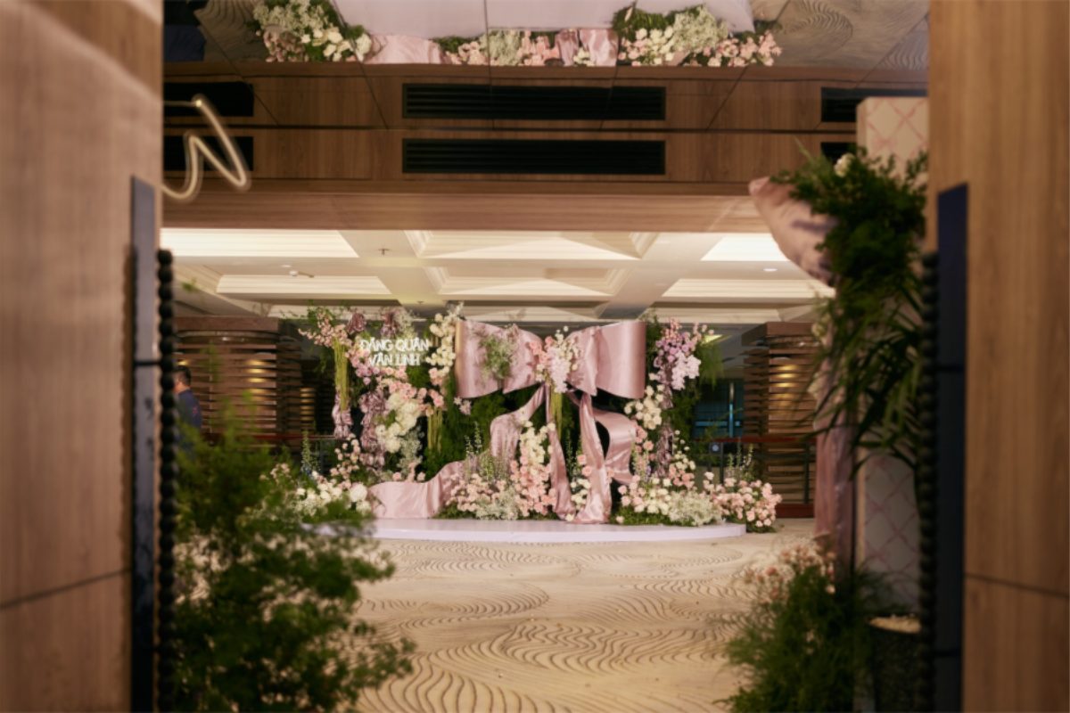 Backdrop photobooth sang trọng tại Pan Pacific Hanoi được trang trí với hoa trắng, lá xanh điểm xuyết nơ hồng lớn làm điểm nhấn tinh tế. (Ảnh: TIFF.vn)