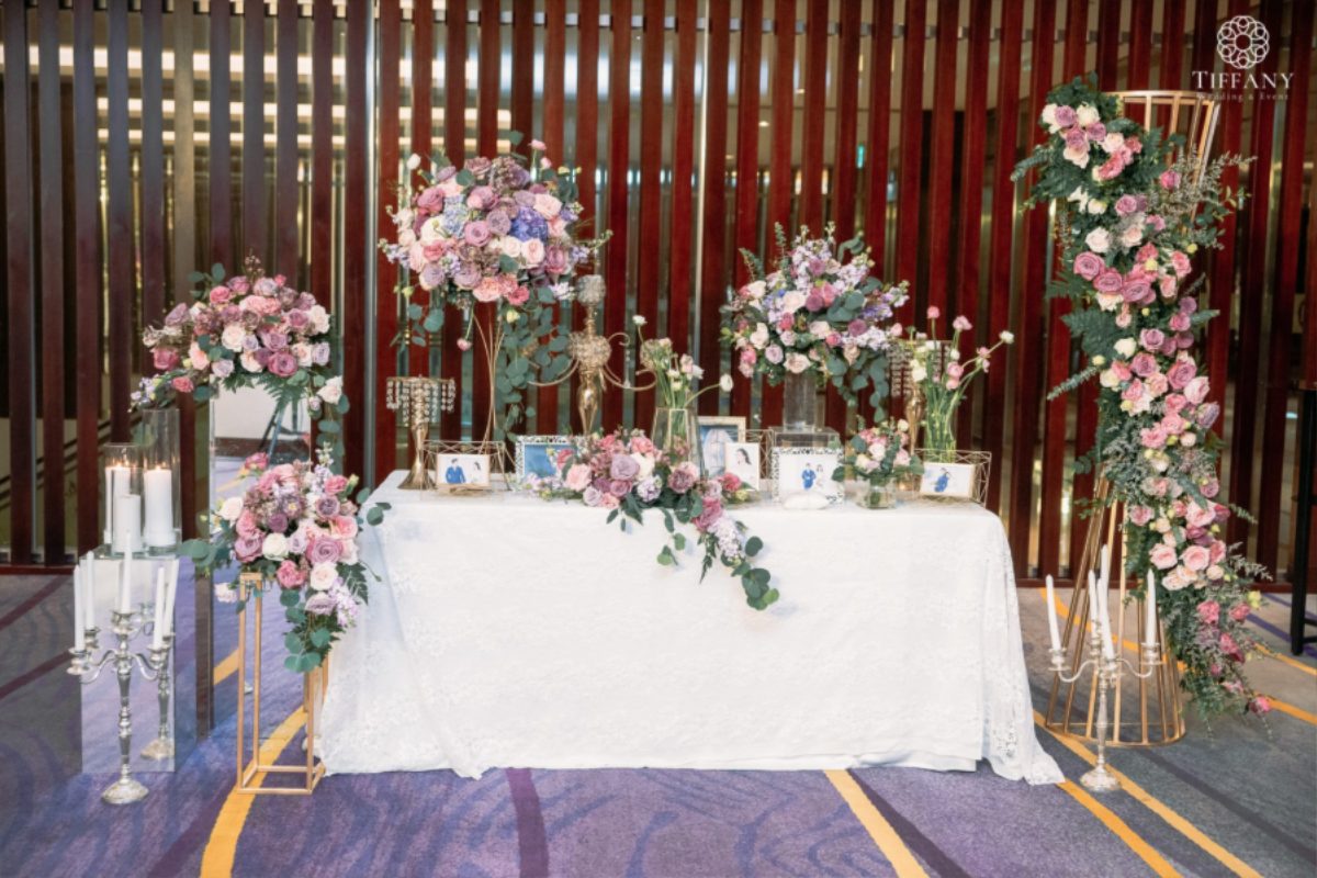 Bàn gallery tiệc cưới trang trí theo tông màu hồng – tím pastel sang trọng, phủ khăn ren trắng tinh khôi. (Ảnh: TIFF.vn)