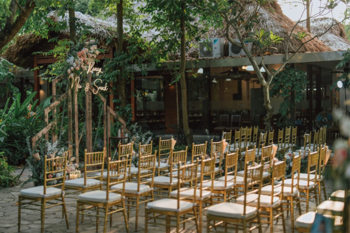 Không gian tổ chức tiệc cưới tại Tổ hợp Công Viên Nhỏ với sân vườn xanh mát, setup bàn tiệc và backdrop lãng mạn, chuẩn bị sẵn bãi đỗ xe rộng rãi cho khách mời. (Ảnh: Sưu tầm)