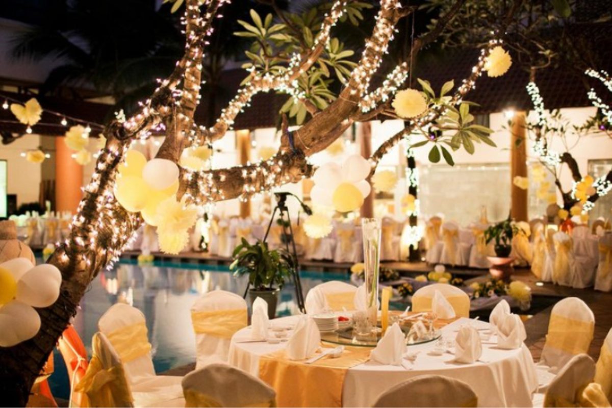 Bàn tiệc quanh hồ bơi, cây xanh bao quanh, ánh đèn vàng và phong cách tropical. (Ảnh: Sưu tầm)