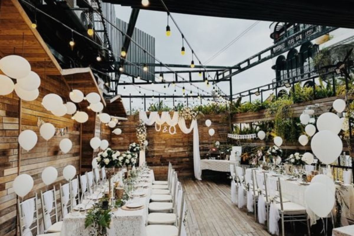 Sân nhỏ với backdrop hoa, bàn ghế gỗ, ánh đèn vàng và không khí gia đình. (Ảnh: Sưu tầm)